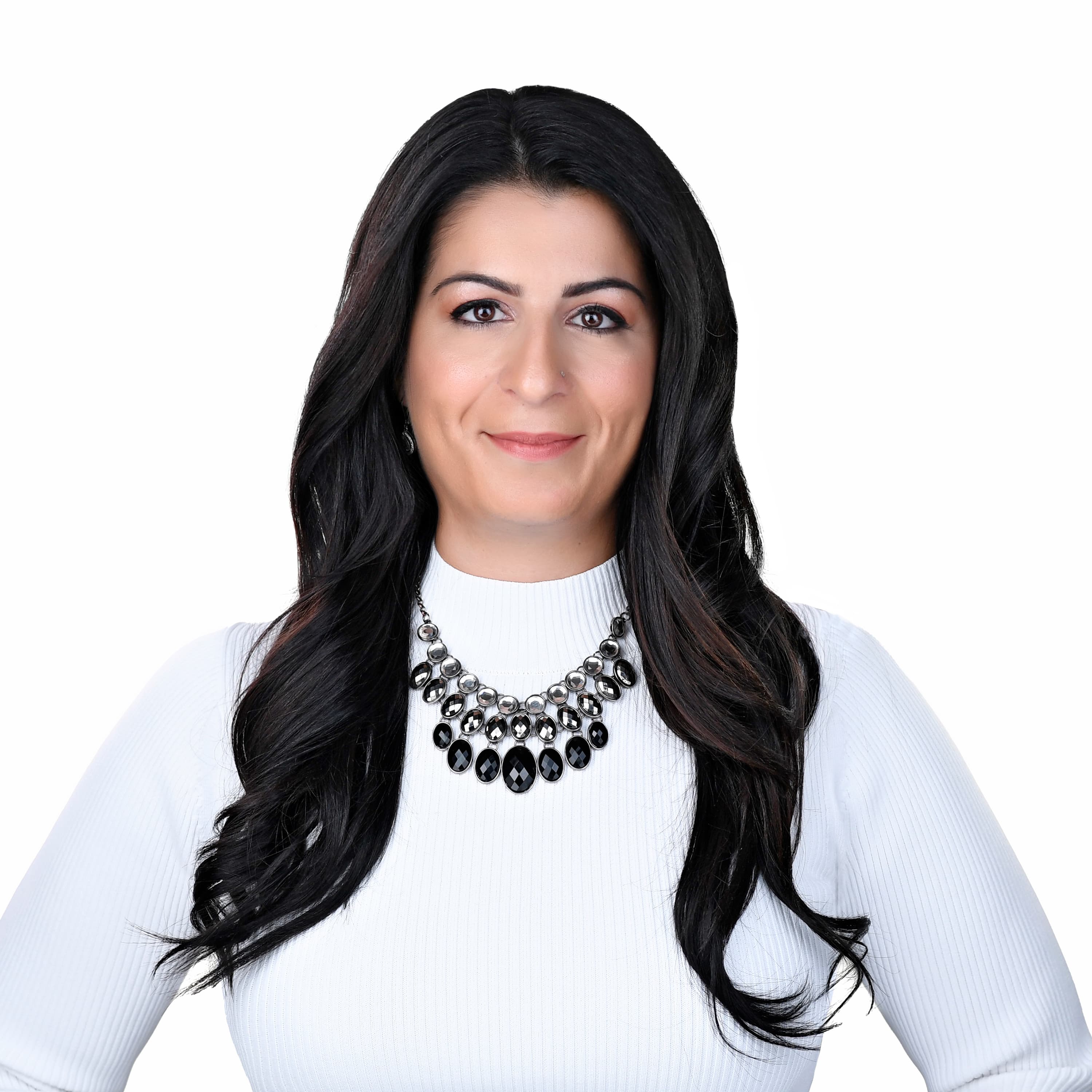Smiling woman with long dark hair, white turtleneck, and a bold black statement necklace.
